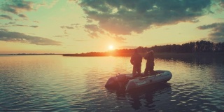 朋友们在夕阳下钓鱼。日落时分，两名业余垂钓者在蚌湖上的船上垂钓