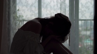 沮丧的年轻美丽的亚洲女人独自坐在公寓卧室的床上哭泣和尖叫。孤独悲伤的女孩，想起悲伤烦恼。消极情绪与心理健康的概念。视频素材模板下载
