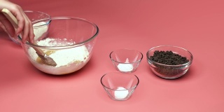 在粉色背景的玻璃碗中加入/混合巧克力片饼干配料:红糖、白糖、巧克力片、鸡蛋、面粉、黄油、香草精、小苏打、4K盐。