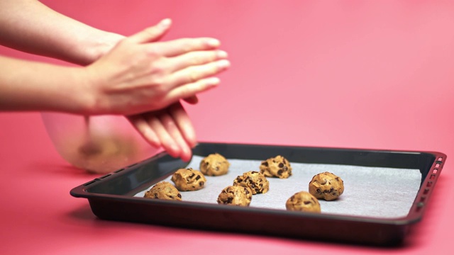 女性双手制作巧克力曲奇生面团碗，并将它们放在一个4K的烹饪托盘锅的烹饪单上。