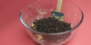 在碗中加入巧克力片和液体巧克力片饼干面团，4K。用慢动作制作饼干面团的概念。