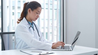 一名年轻的亚洲医生在医院用笔记本电脑工作的4K视频视频素材模板下载