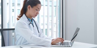 一名年轻的亚洲医生在医院用笔记本电脑工作的4K视频