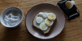 把小碗里的盐撒在带鸡蛋的白面包上