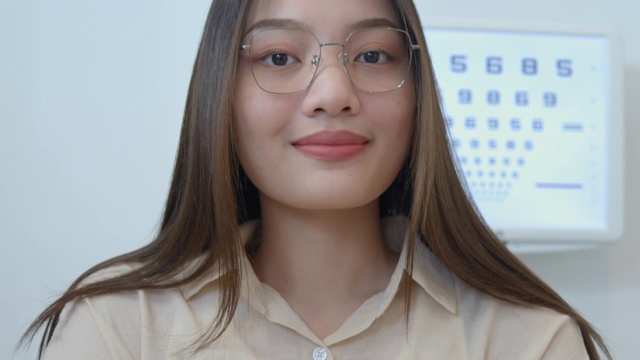 年轻的亚洲女人尝试新的眼镜在光学商店