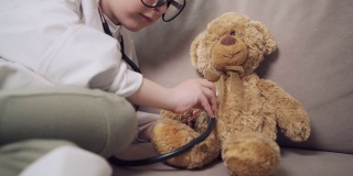 一个女孩扮演医生，用语音内窥镜听玩具熊说话。