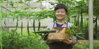 一位华裔女性中年女农民在温室里开心地看着镜头