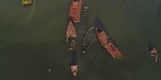 在美国纽约市史泰登岛的船墓地上沉没的生锈的废弃船只。向下看，正上方的航拍视频由无人机，与轨道摄像机运动。