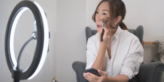 一位美丽的亚洲化妆博主正在家中直播如何化妆