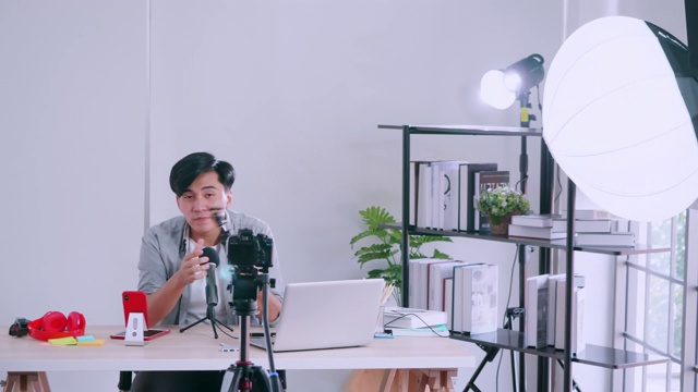 一名亚洲年轻人通过摄像机直播指导某样东西并分享到社交媒体上。