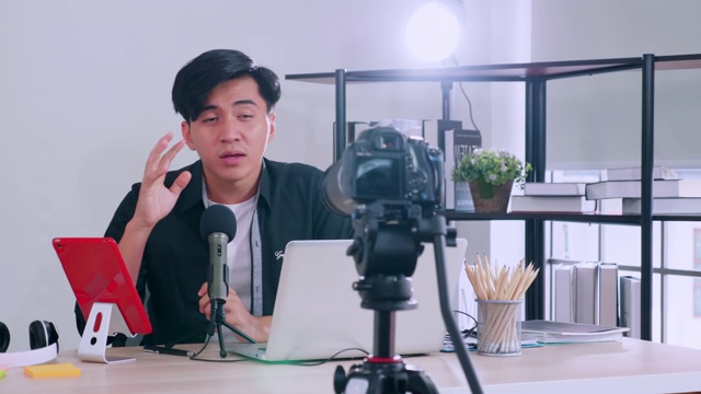一名亚洲年轻人通过摄像机直播指导某样东西并分享到社交媒体上。