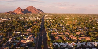 空中镜头凤凰城，亚利桑那州飞在驼峰路和山在傍晚的太阳发光的红色。