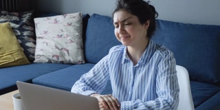 一个年轻的印度妇女是沮丧和担心在电脑上工作，她是担心一个坏的结果，她看到，她是在家里和工作在网上