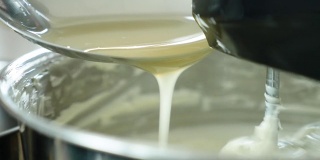 近距离观察搅拌机搅拌美味奶油制作蛋糕的过程。