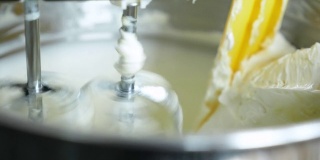 近距离观察搅拌机搅拌美味奶油制作蛋糕的过程。
