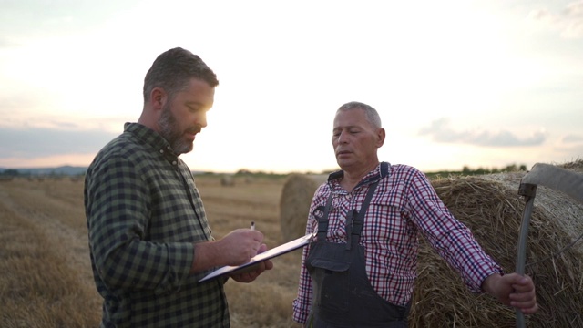 一位资深农民在农田里与一位农学家谈话