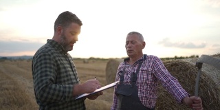 一位资深农民在农田里与一位农学家谈话