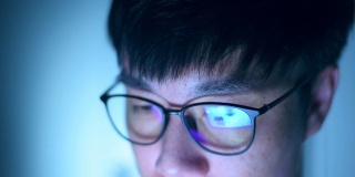 近距离的亚洲年轻人戴着眼镜看电脑