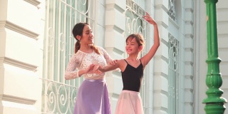 在一个阳光明媚的日子里，一名亚洲青少年芭蕾舞演员在一名年轻女芭蕾舞老师的建议下，在泰国曼谷当地的街道上练习芭蕾舞。活跃的年轻妇女和孩子的概念周末活动和当地地标。