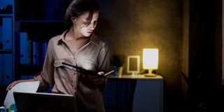 亚洲女性在家里的电子平板电脑上写作或做笔记。