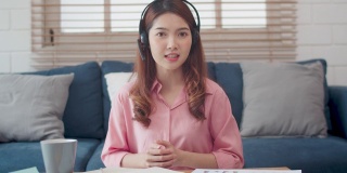 亚洲女商人戴着耳机在家通过网络摄像头进行电话会议。社会电话会议的概念