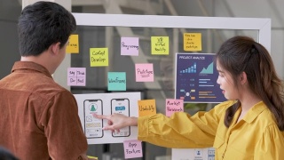 亚洲用户体验开发人员和UI设计师在现代办公室会议的白板上展示和测试手机应用界面设计。创意数字开发移动应用机构视频素材模板下载