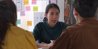 亚洲用户体验开发人员和UI设计师在现代办公室的桌子上进行关于移动应用界面线框图设计的头脑风暴。创意数字发展机构
