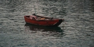 一艘红色的小渔船在平静的水面上抛锚