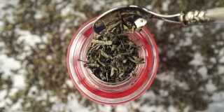 绿茶。干燥的卷叶落入玻璃茶壶特写