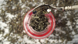 绿茶。干燥的卷叶落入玻璃茶壶特写视频素材模板下载