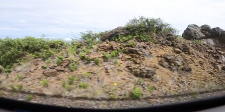 POV从车的后视镜看下山，显示了美丽的山景在路边。慢动作，高角度视图。夏威夷群岛。