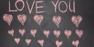 用粉红色的粉笔写一段爱你的文字，在黑色的黑板上画许多心。定格动画和情人节和婚礼的概念