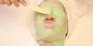 一位年轻女子在脸上敷了一层绿藻年轻化面膜