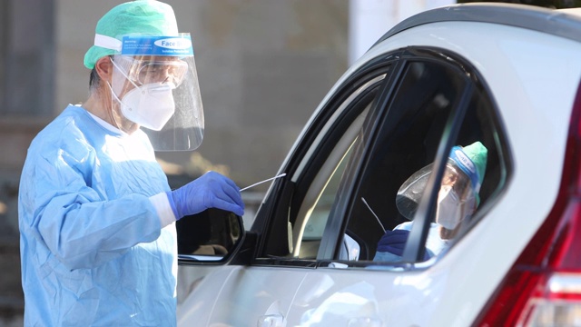 医护人员佩戴EPI对车内的患者进行PCR检测，以检测患者是否感染COVID-19