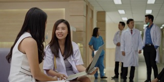 亚洲医生在医院里咨询健谈的女病人。专科医师为人民服务心灵。工作场所清洁，没有冠状病毒。结束隔离，返回开放医疗