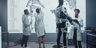 在机器人开发实验室:女工程师和男科学家工作与大屏幕显示机器人外骨骼原型设计。为帮助残疾人、繁重劳动工人建造防弹衣