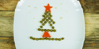 有趣的可食用圣诞树，由豌豆和胡萝卜制成，给孩子们的早餐主意。新年食物背景俯视图。节日、庆典、美食艺术概念