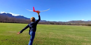 男孩喜欢把他的玩具飞机扔到操场上