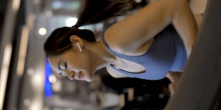 年轻漂亮的女人在健身房锻炼在跑步机上跑步