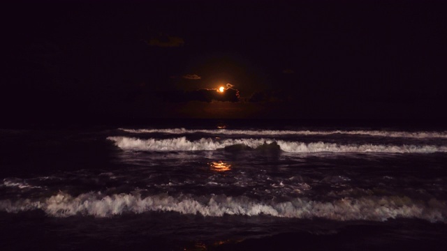 一轮满月在海浪上升起。戏剧性的日落海滩视频