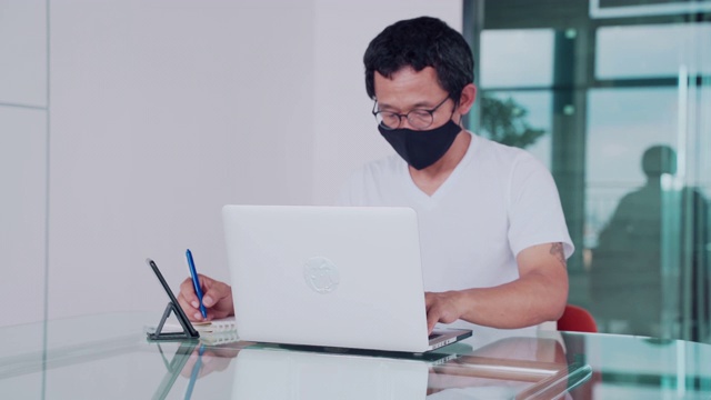 穿着休闲服的亚洲人，戴着口罩以保护自己免受冠状病毒感染。在网上搜索和申请工作。,社会距离