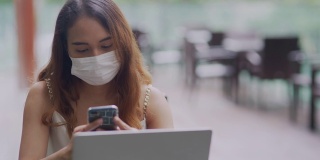 年轻的亚洲女性在使用笔记本电脑和智能手机时注意力集中