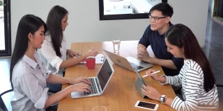 一群年轻的亚洲商务人士团队在现代办公室的共同办公空间开会讨论商业计划和头脑风暴。企业家男士提出战略，与女性合作