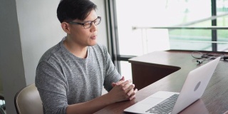 新冠肺炎疫情期间，亚洲年轻商人利用笔记本电脑召开视频会议，与居家隔离的同事进行在线工作交流
