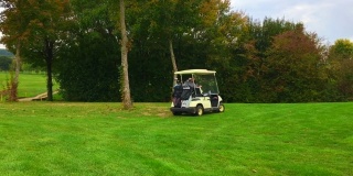高尔夫球手驾驶高尔夫球车与高尔夫球袋在高尔夫球场