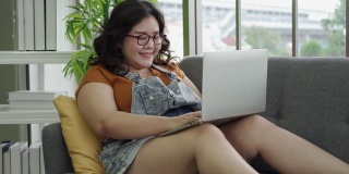 亚洲体型庞大的女性在笔记本电脑上打字，在家工作