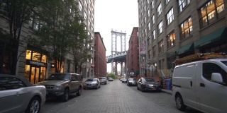 慢镜头:从小飞象那里看布鲁克林大桥，小飞象公寓和路边停着的汽车在夏天清晨的阳光下