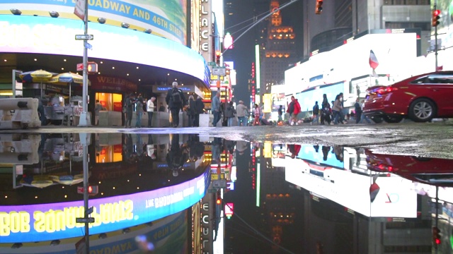 曼哈顿之夜，纽约时报广场的灯光在雨后的水坑中反射