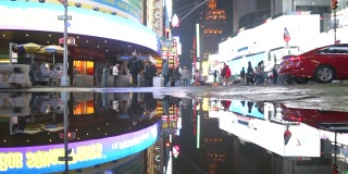 曼哈顿之夜，纽约时报广场的灯光在雨后的水坑中反射