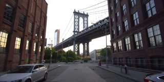 慢镜头:从小飞象那里看布鲁克林大桥，小飞象的公寓和路边停着的汽车在夏天的清晨与跑步者擦肩而过